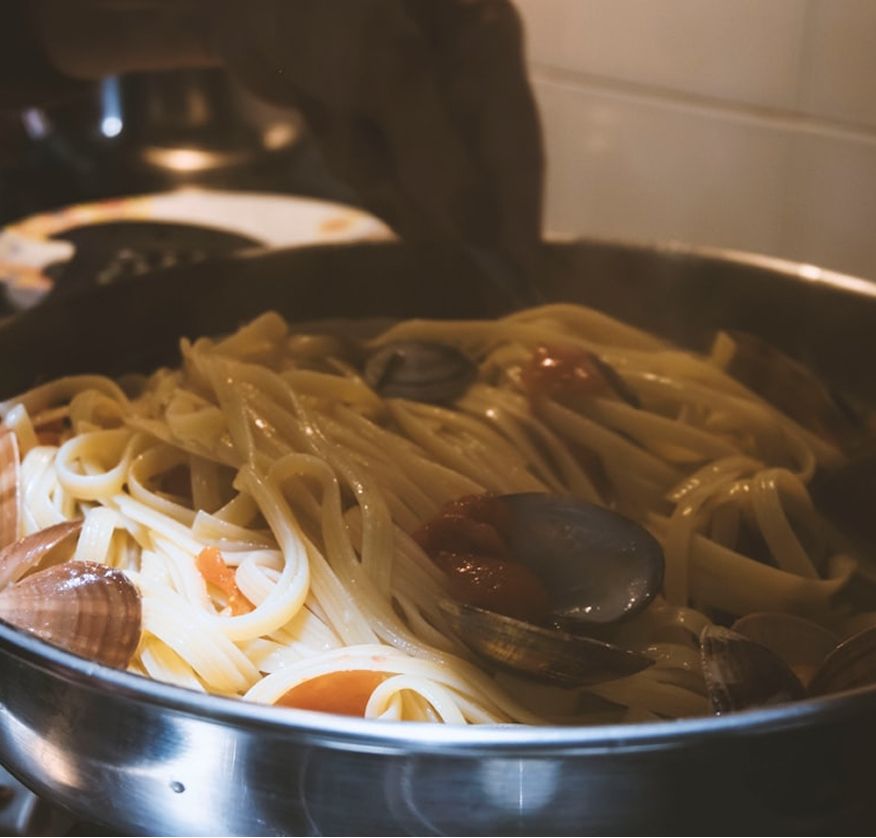 A pan of linguine tossed with clams and cherry tomatoes, ready to be plated