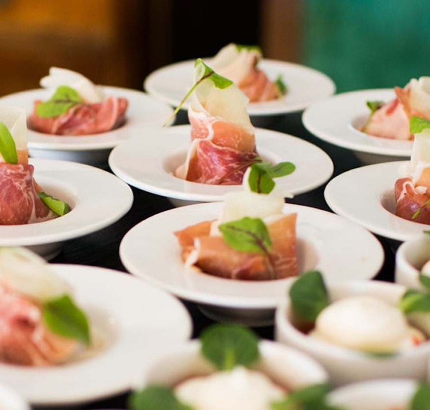 Prosciutto-wrapped melon canapés garnished with mint, plated individually for serving